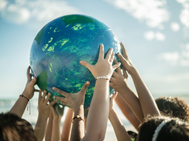 Close-up of children holding a planet at the beach