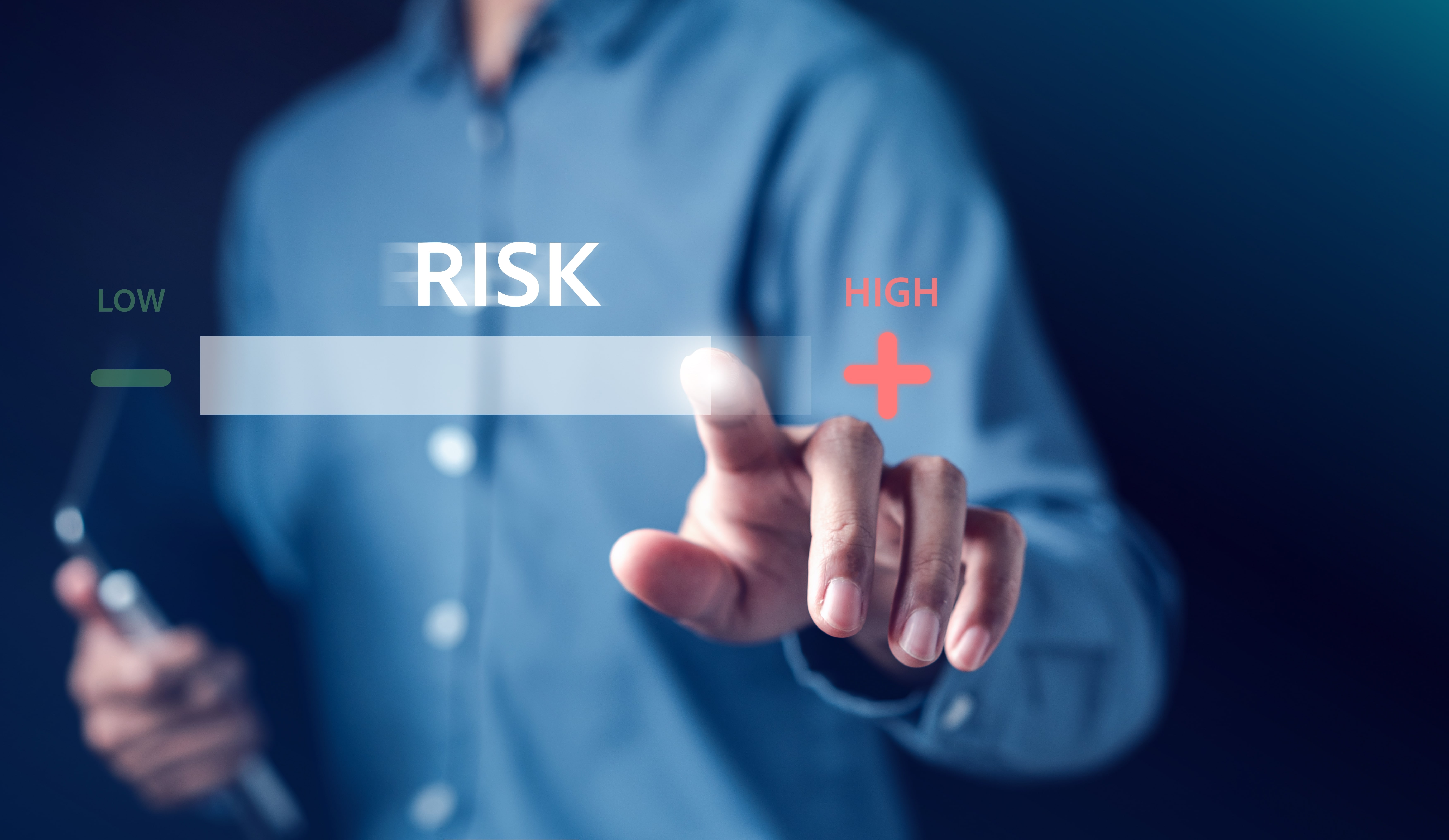Ein Mann streicht über eine Glasscheibe, auf der "LOW", "RISK" und "HIGH" geschrieben steht.