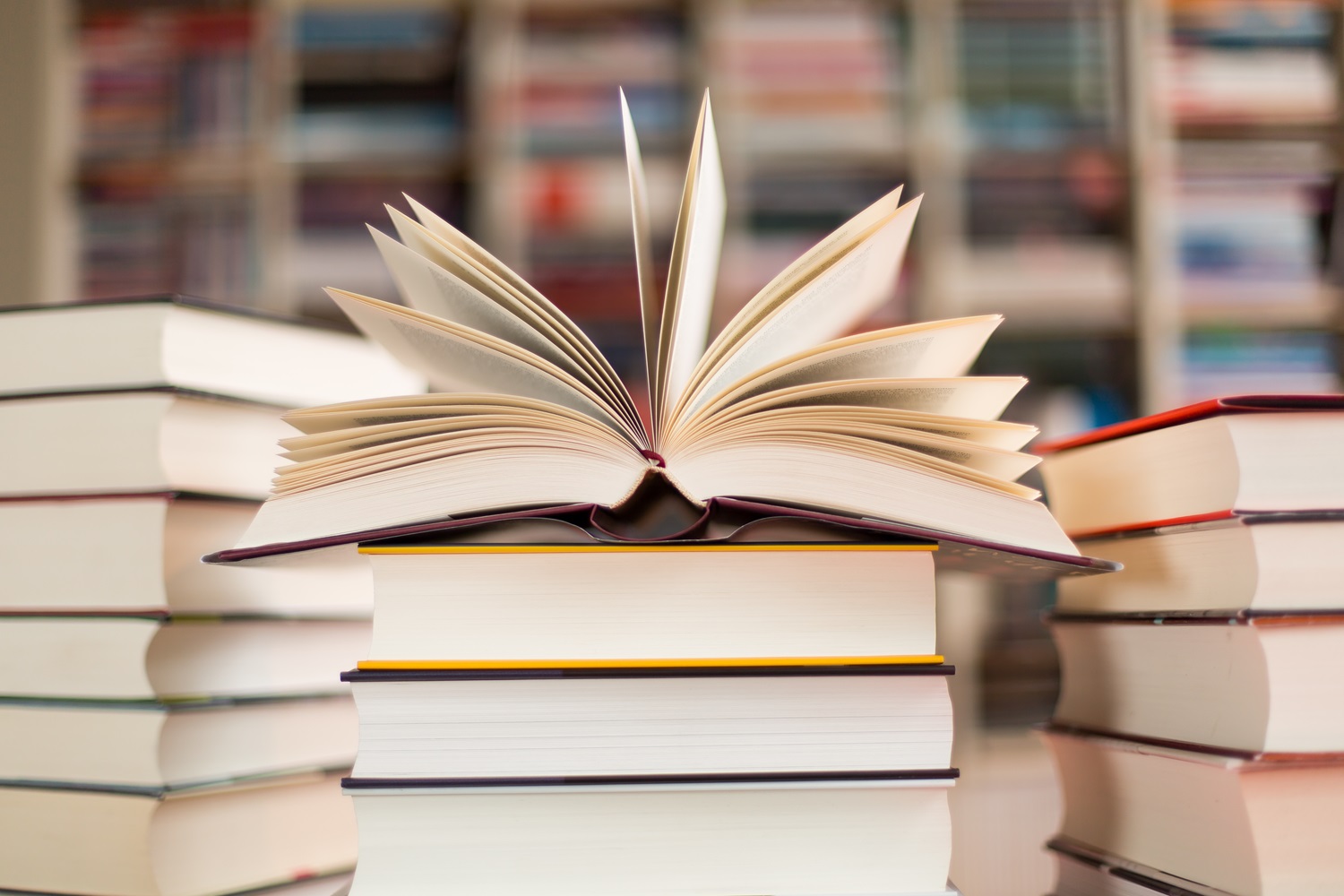 Ein aufgeklapptes Buch liegt auf einem Stapel von Büchern.