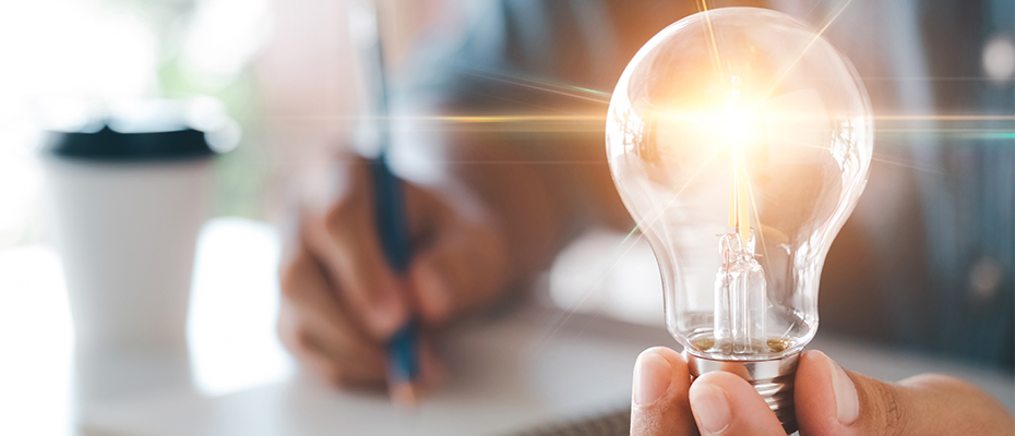 Eine Hand hält eine leuchtende Glühbirne.