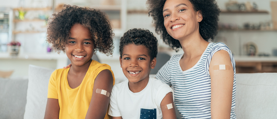 Eine Frau und zwei Kinder, alle haben ein Pflaster auf dem Oberarm.