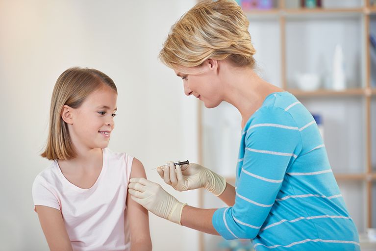 Ein Mädchen bekommt eine Impfung in den Oberarm.