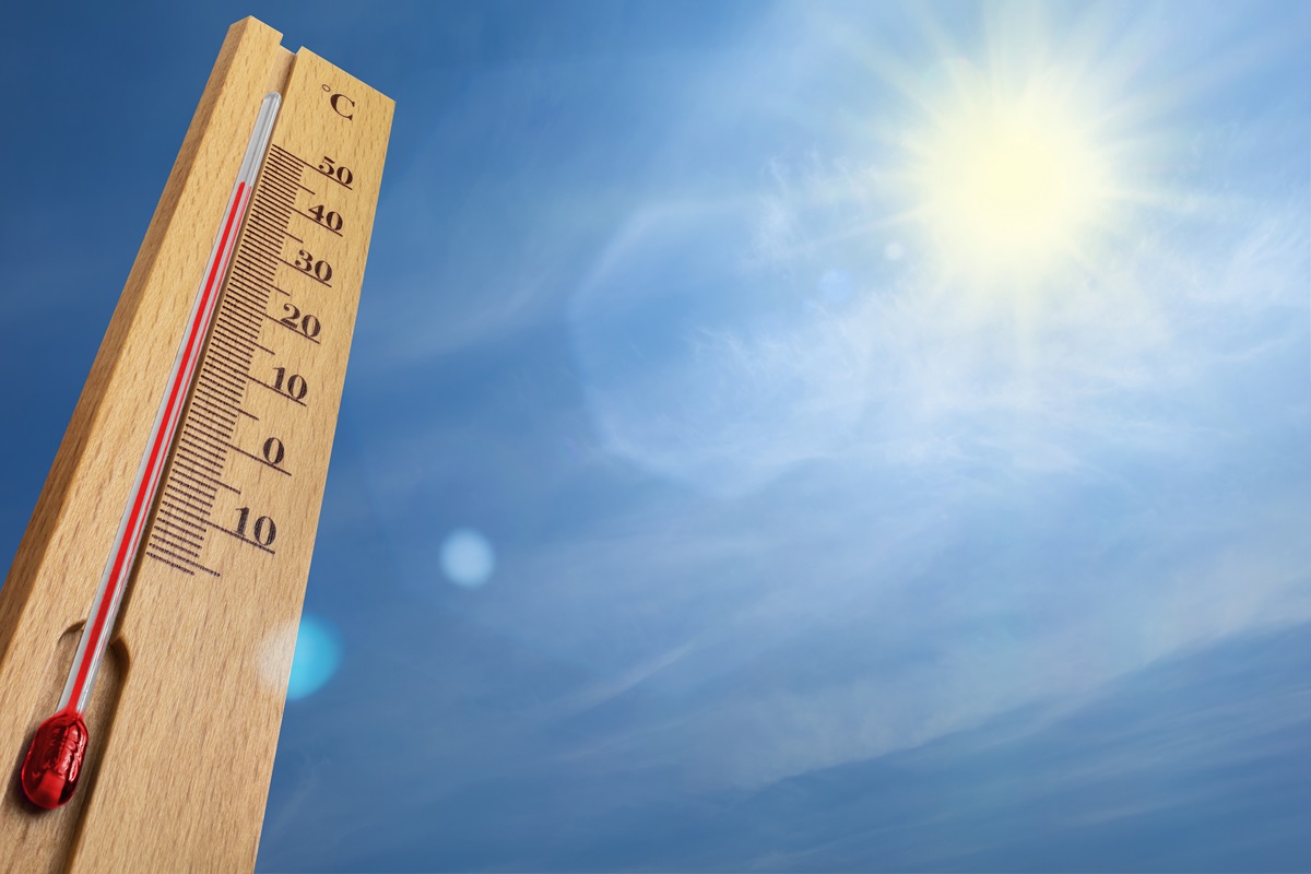 Ein Thermometer ragt in einen Himmel mit strahlender Sonne.