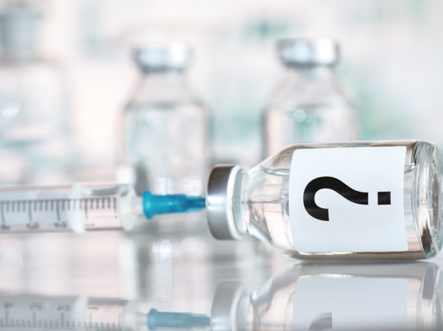 Spritze, mit der Impfstoff aufgezogen wird, Impfstoff ist mit einem großen Fragezeichen beschriftet