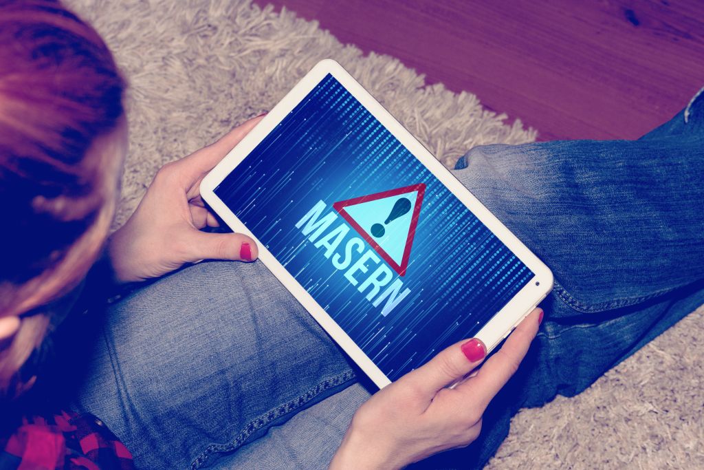 Frau hält ein Tablet in den Händen und bildet ein rotes Dreieck mit Ausrufezeichen ab und darunter steht Masern
